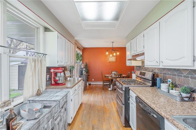 kitchen with black dishwasher, light countertops, white cabinetry, under cabinet range hood, and double oven range