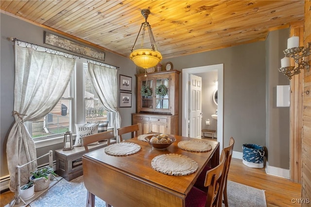 dining space with light wood-type flooring, ornamental molding, baseboards, and wooden ceiling