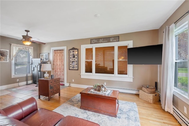 living room with a baseboard radiator, light wood finished floors, baseboard heating, and a healthy amount of sunlight