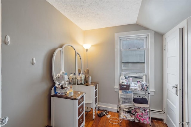 interior space with baseboards, a textured ceiling, wood finished floors, and vaulted ceiling