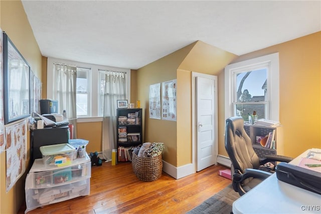 home office featuring baseboards, a baseboard heating unit, and wood finished floors