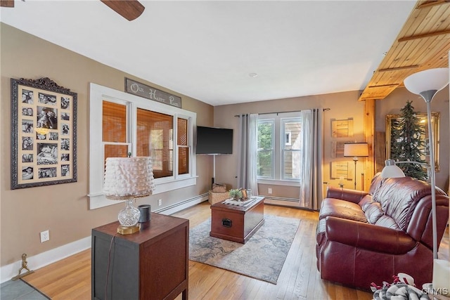living room with a ceiling fan, baseboards, baseboard heating, and light wood-style floors
