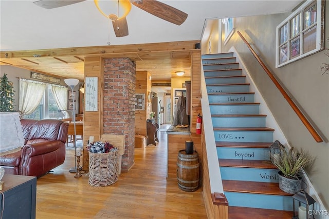 stairs featuring a ceiling fan, wood finished floors, and wood walls