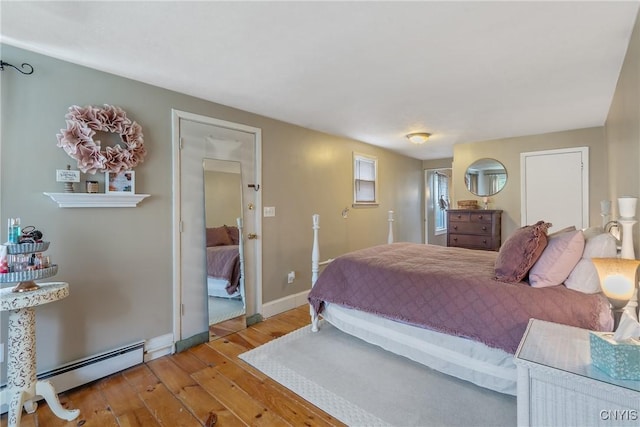 bedroom featuring baseboards, baseboard heating, and hardwood / wood-style flooring