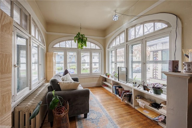 sunroom featuring french doors, wood finished floors, and radiator heating unit