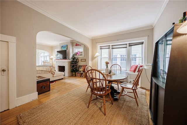 dining space featuring crown molding, arched walkways, a wealth of natural light, and wood finished floors