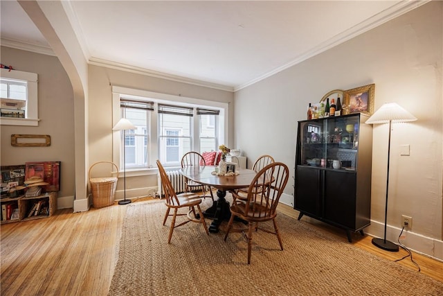 dining space featuring crown molding, arched walkways, and wood finished floors
