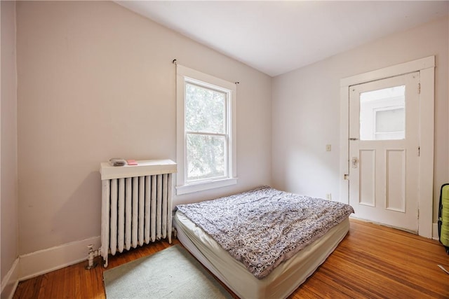 bedroom featuring baseboards, wood finished floors, and radiator