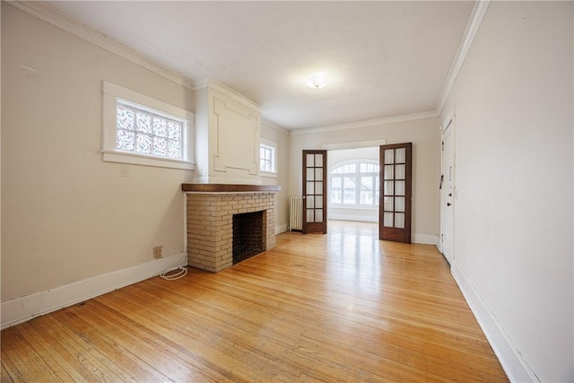 unfurnished living room with light wood-style floors, ornamental molding, radiator, and a healthy amount of sunlight