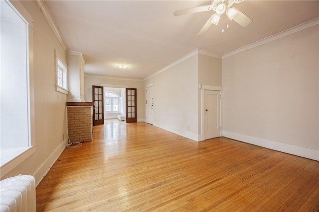 interior space featuring radiator heating unit, crown molding, a ceiling fan, and light wood-type flooring