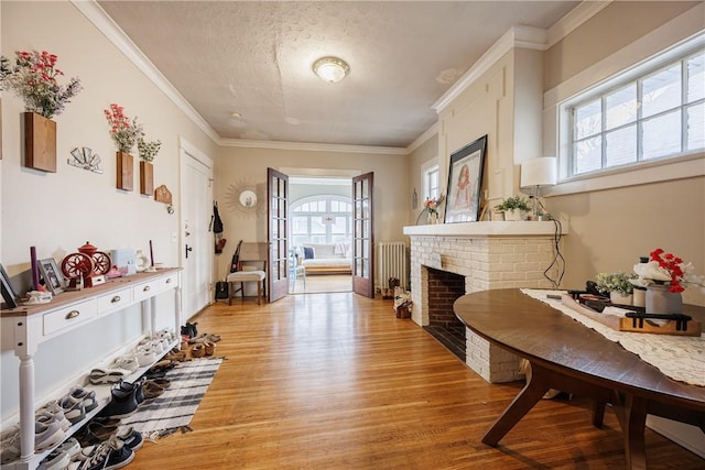 sitting room with crown molding, radiator, a fireplace, and light wood-type flooring