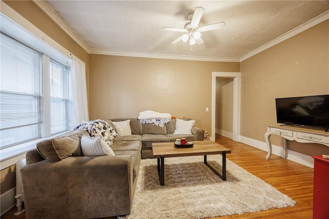 living area with baseboards, a ceiling fan, wood finished floors, and ornamental molding