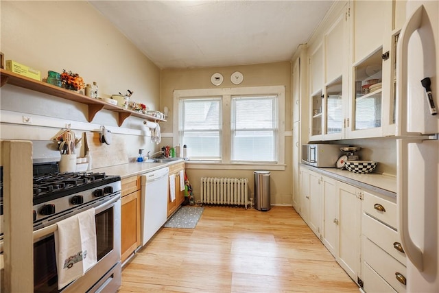 kitchen featuring appliances with stainless steel finishes, open shelves, light wood-type flooring, light countertops, and radiator heating unit