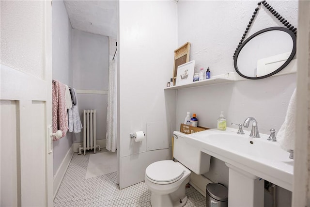 bathroom with a sink, radiator, and toilet