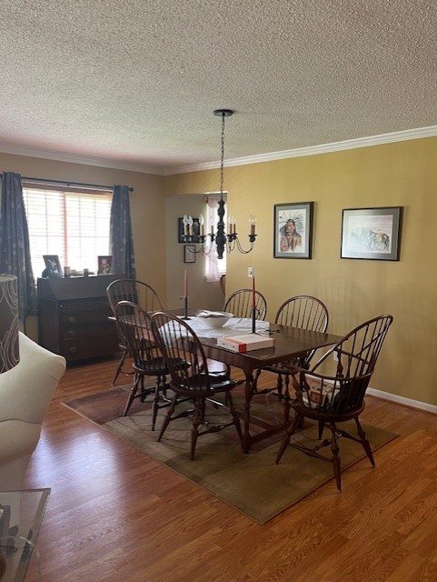 dining room featuring wood finished floors, a textured ceiling, and a notable chandelier