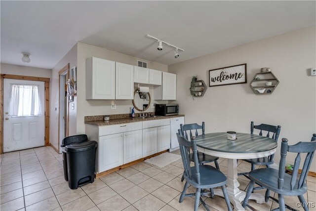 25082 Ridge Rd, Watertown-Town, NY 13601 - kitchen featuring visible vents, dark countertops, white cabinetry, stainless steel microwave, and light tile patterned floors