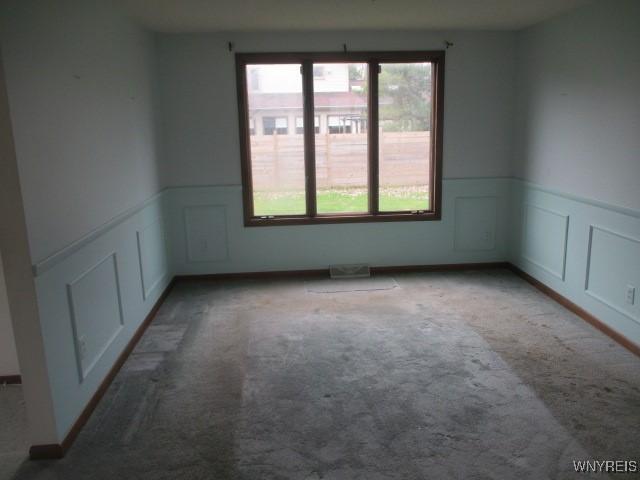carpeted spare room with a wainscoted wall and a decorative wall