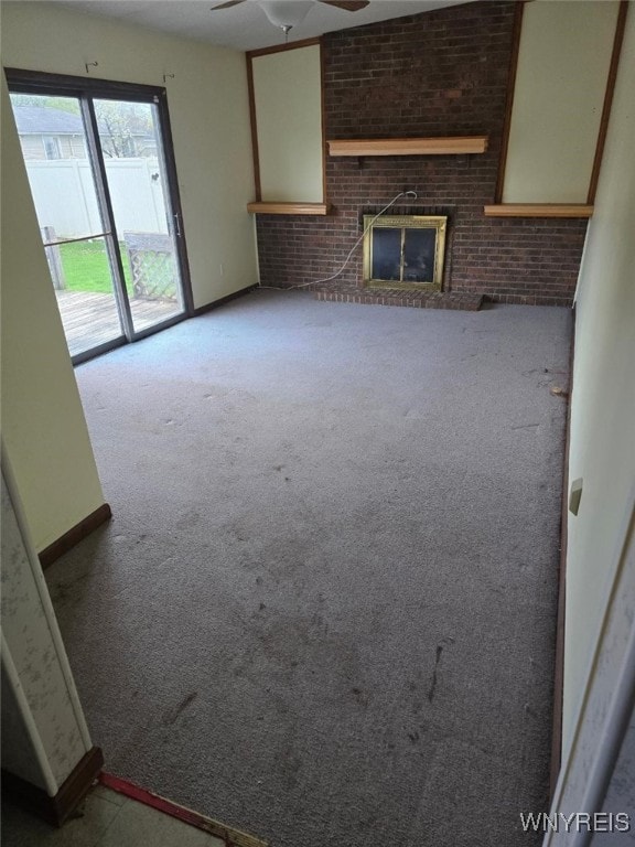 unfurnished living room with baseboards, a ceiling fan, carpet flooring, and a brick fireplace