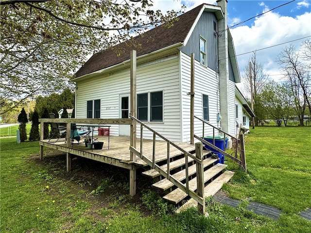 back of property with a shingled roof, a yard, a deck, and a chimney