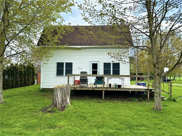 back of house featuring a lawn, a shingled roof, and a deck
