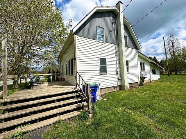 view of side of property featuring a lawn, a wooden deck, and a chimney