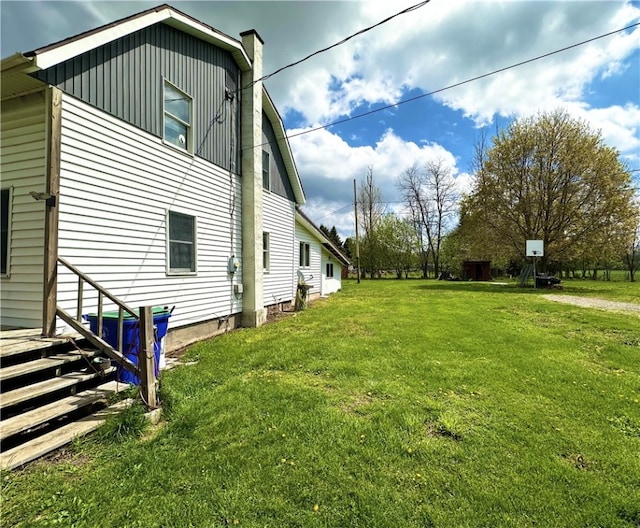 view of side of home featuring a chimney and a yard
