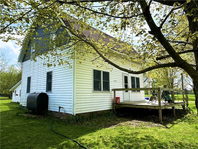 back of house with a wooden deck, heating fuel, and a yard