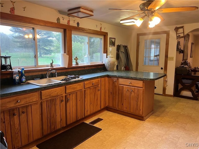 kitchen featuring a sink, light floors, dark countertops, and visible vents