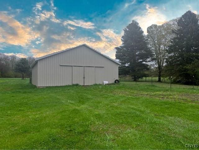 outdoor structure at dusk with a lawn and an outbuilding