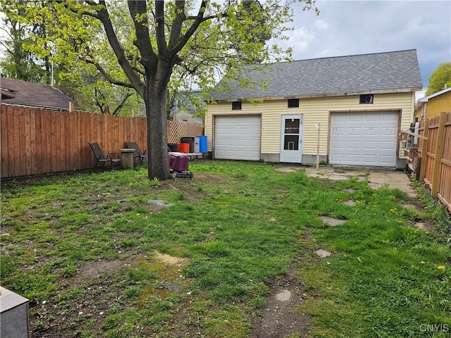 view of yard with fence, an outdoor structure, and a garage