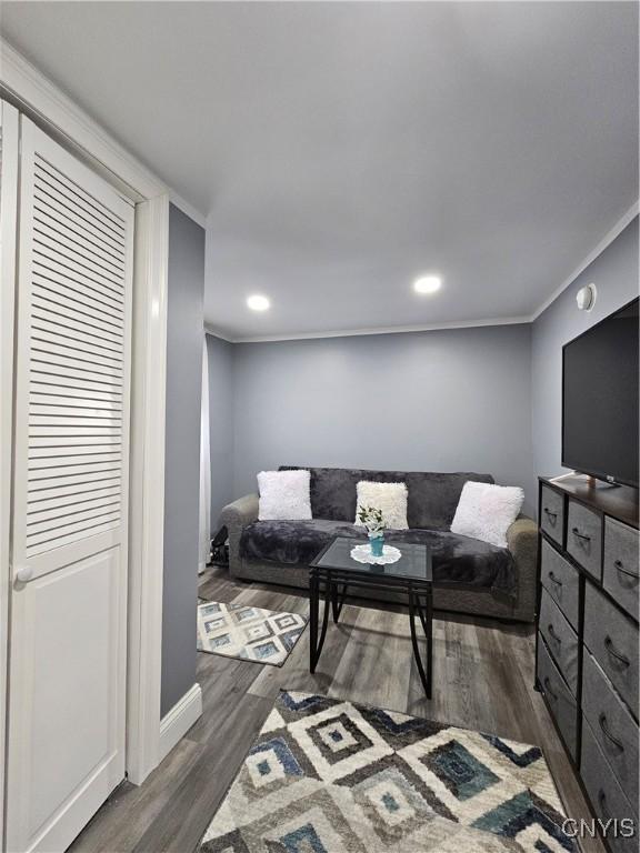 living area featuring crown molding, baseboards, recessed lighting, and dark wood finished floors