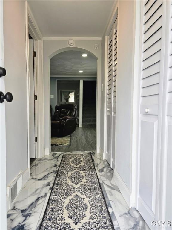 corridor featuring arched walkways, baseboards, visible vents, and marble finish floor