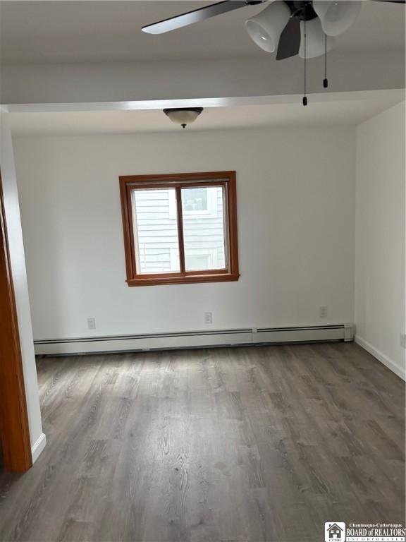 empty room with a ceiling fan, baseboards, wood finished floors, and a baseboard radiator