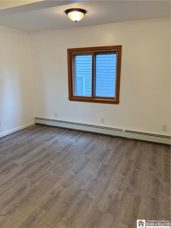 unfurnished room featuring baseboards, a baseboard radiator, and wood finished floors