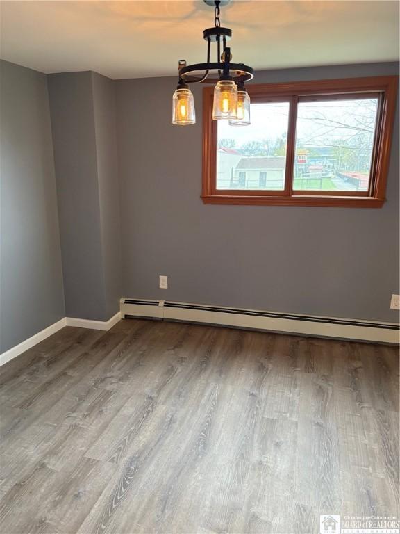 unfurnished room featuring baseboards, a chandelier, baseboard heating, and wood finished floors