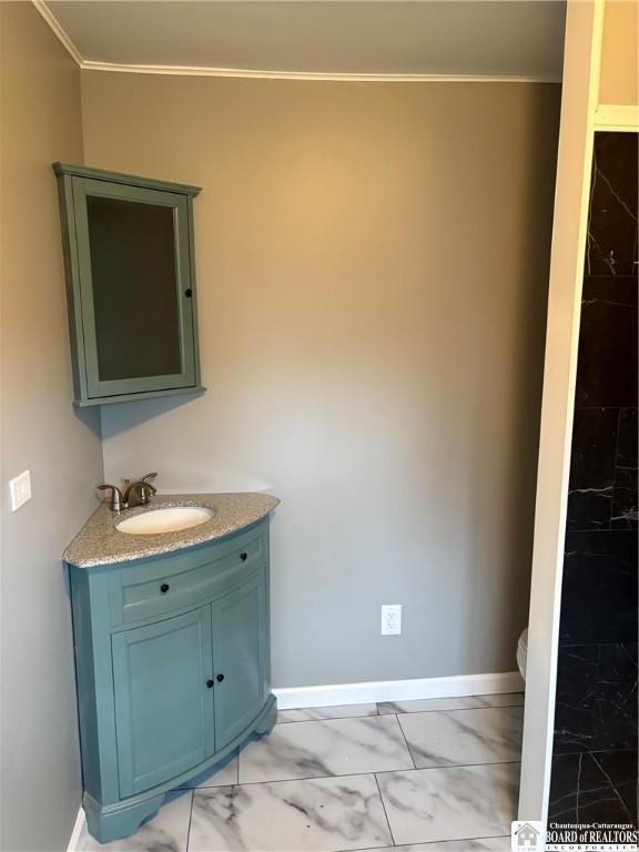 bathroom featuring vanity, baseboards, toilet, marble finish floor, and ornamental molding
