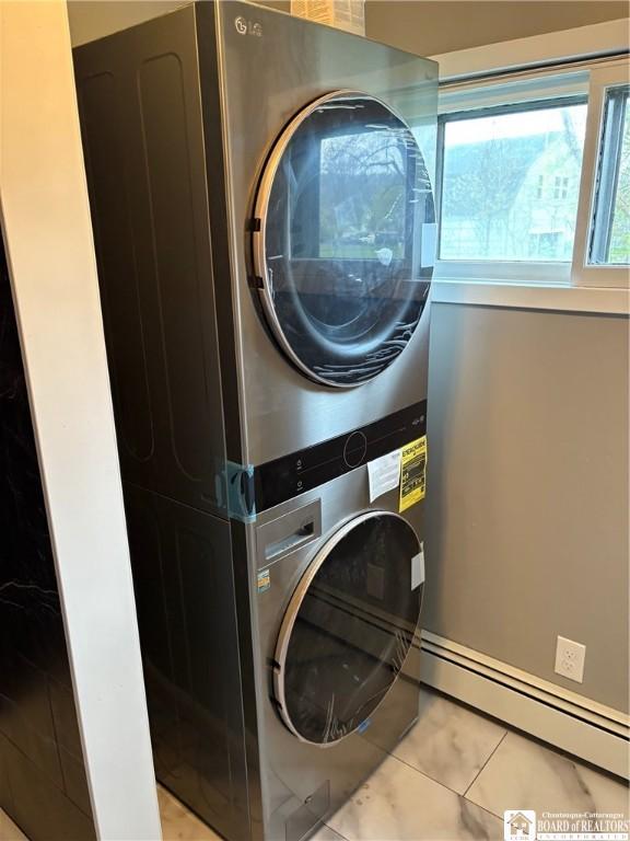 laundry area with tile patterned floors, a baseboard radiator, and stacked washer and clothes dryer