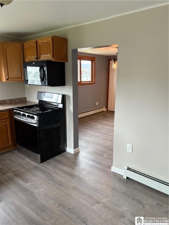 kitchen with a baseboard heating unit, ornamental molding, black microwave, and stainless steel gas stove