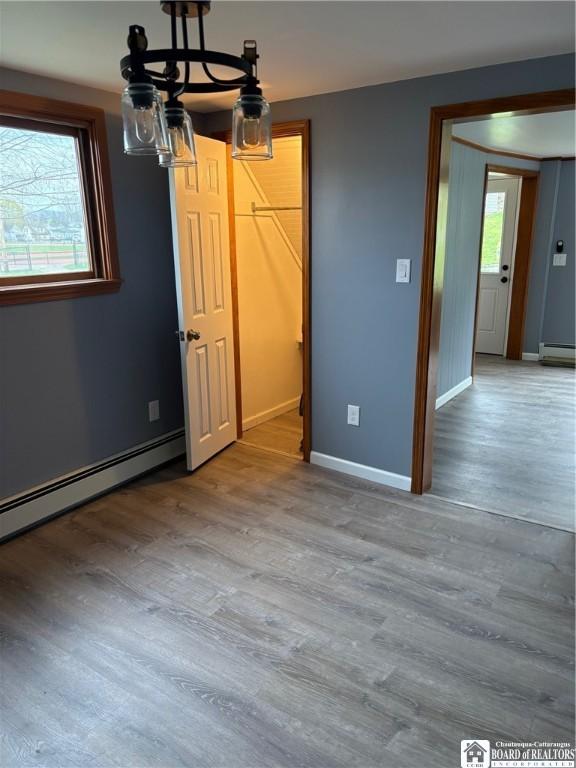 interior space with baseboards, a baseboard heating unit, wood finished floors, and baseboard heating