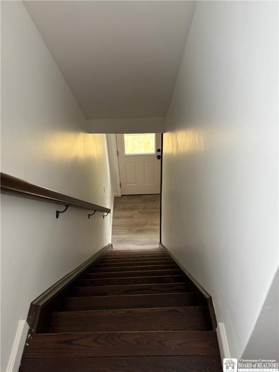 staircase with baseboards, wood finished floors, and vaulted ceiling