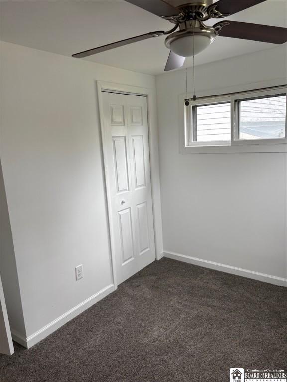 unfurnished bedroom featuring baseboards, ceiling fan, and dark carpet