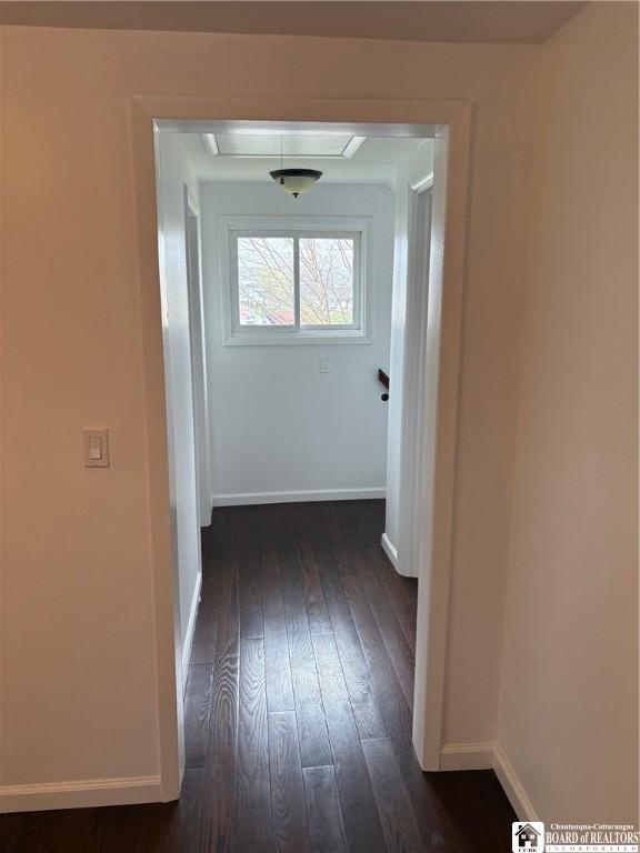 corridor with baseboards and dark wood-type flooring