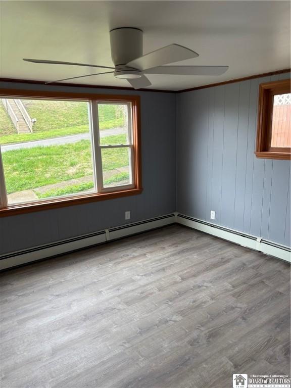 empty room featuring ceiling fan, a wealth of natural light, and wood finished floors