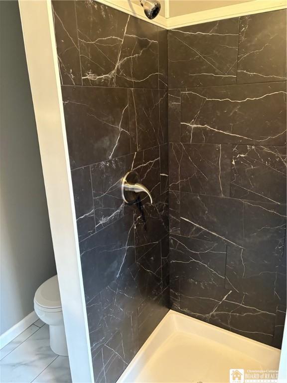 full bath with marble finish floor, walk in shower, and toilet