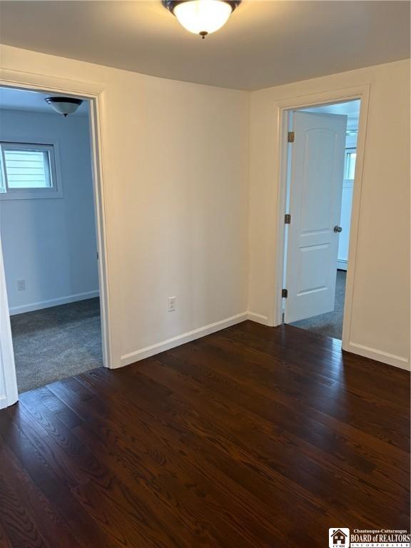 unfurnished room with baseboards and dark wood finished floors