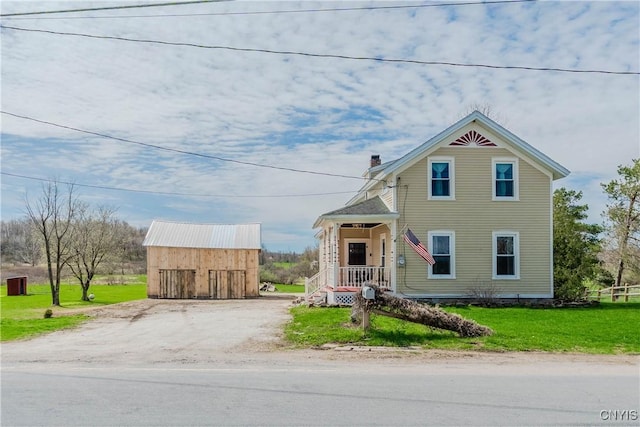 victorian home with a porch, a chimney, an outbuilding, and a front yard