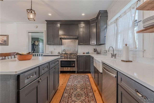 kitchen featuring pendant lighting, light countertops, a sink, backsplash, and stainless steel appliances