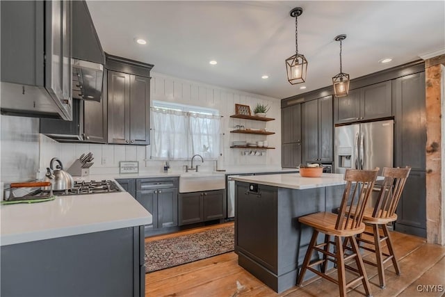 kitchen featuring open shelves, appliances with stainless steel finishes, a sink, a kitchen breakfast bar, and a kitchen island