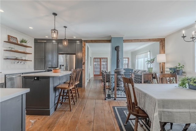 kitchen featuring open shelves, light countertops, stainless steel appliances, a kitchen bar, and ornamental molding