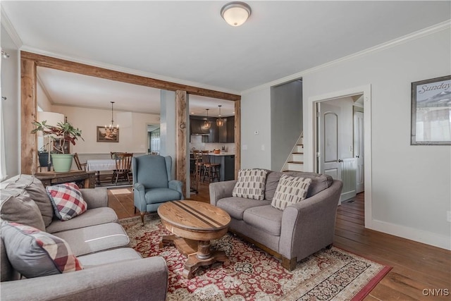living room featuring crown molding, baseboards, a chandelier, stairs, and hardwood / wood-style floors